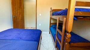 Ein Zimmer mit Etagenbetten, einer Holztür und einem Fliesenboden.