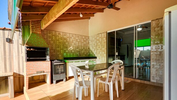 Ein Außenküchenbereich mit Grill, einem Esstisch mit Stühlen und einer Schiebetür, die auf eine Terrasse führt.