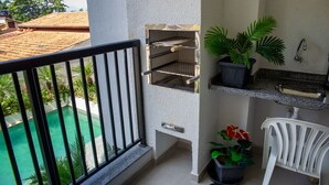 Un balcone con vista su una piscina, un barbecue e piante in vaso.