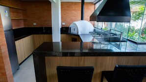 Una cucina moderna con forno a incasso, frigorifero e angolo bar con due sedie.