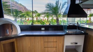 Una cucina con piano di lavoro in legno, piano cottura integrato e vista su piante tropicali.