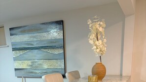 Een moderne keuken met een marmeren aanrecht, een houten vaas met bloemen, en een groot abstract schilderij aan de muur.