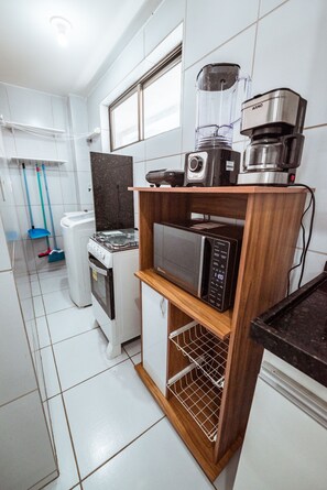 A compact kitchen with a microwave, a coffee maker, and a blender on a wooden shelf. - Apartamento com Garagem a 200m da Praia do Bessa (João Pessoa)