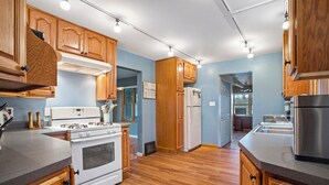 A kitchen with wooden cabinets, a white stove, and a stainless steel refrigerator.