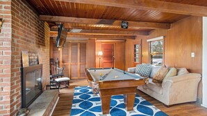 A cozy room with a pool table, a fireplace, and a comfortable seating area.
