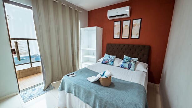 A bedroom with a bed, a wardrobe, a balcony, and a view of the sea. - Casa em Jacum com Piscina 5 Suites e Fliperama (Conde)