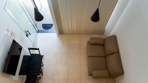 A modern living area with a sofa and a dining table with chairs. - Loft c Ar Smart Lock e Wi-fi no Cora o do Itagu (Ubatuba)