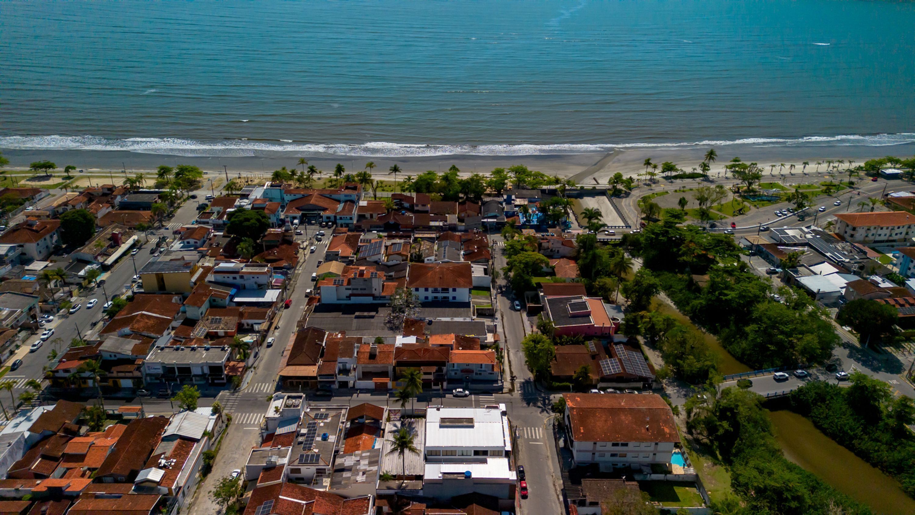 Una vista aerea di una cittadina costiera con edifici residenziali, una spiaggia e un fiume.