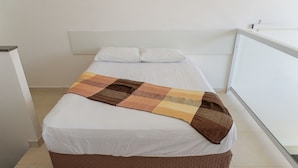A neatly made bed with a brown and beige blanket, white pillows, and a white headboard. - Loft com Wi-fi e Smart Lock Perto do Projeto Tamar (Ubatuba)