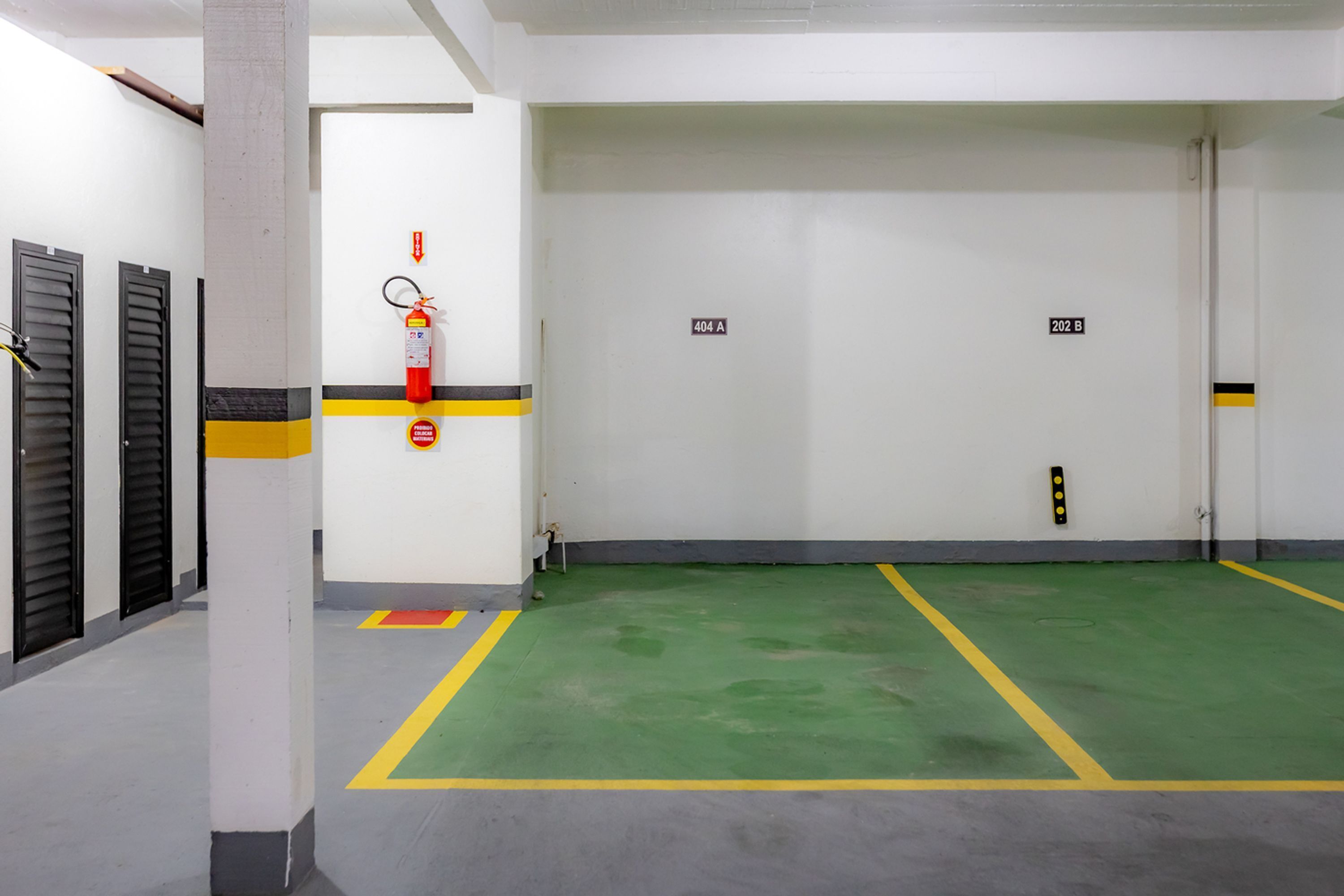 A clean, well-lit indoor space with a green floor, white walls, and numbered doors.