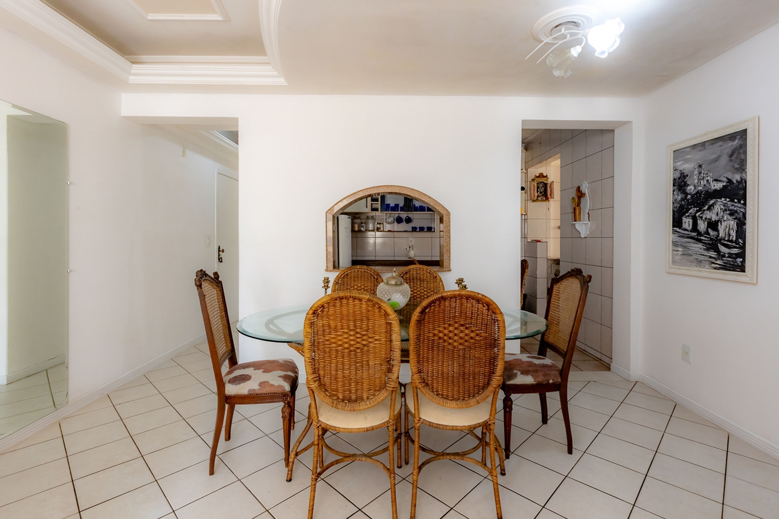 A dining area with a glass-top table and four wicker chairs.