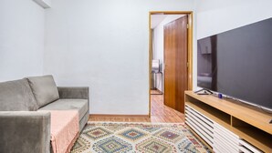 A small, modern living room with a grey sofa, a flat-screen TV on a wooden stand, and a patterned rug. - Apartamento c Fechadura Eletr Nica a 200m do Metr (São Paulo)