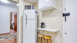 A compact kitchen with a refrigerator, a coffee maker, and two stools. - Apartamento c Fechadura Eletr Nica a 200m do Metr (São Paulo)
