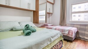 A bedroom with a bed, a small bedside table, a mirror, and a window with curtains. - Apartamento c Fechadura Eletr Nica a 200m do Metr (São Paulo)
