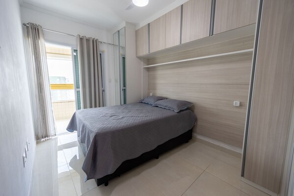 Quarto com cama, guarda-roupa e espelho.