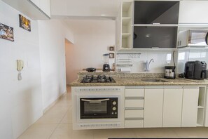 A modern kitchen with a built-in oven, microwave, and gas stove. - Apto com Varanda e Churrasqueira a 100m da Orla (Praia Grande)