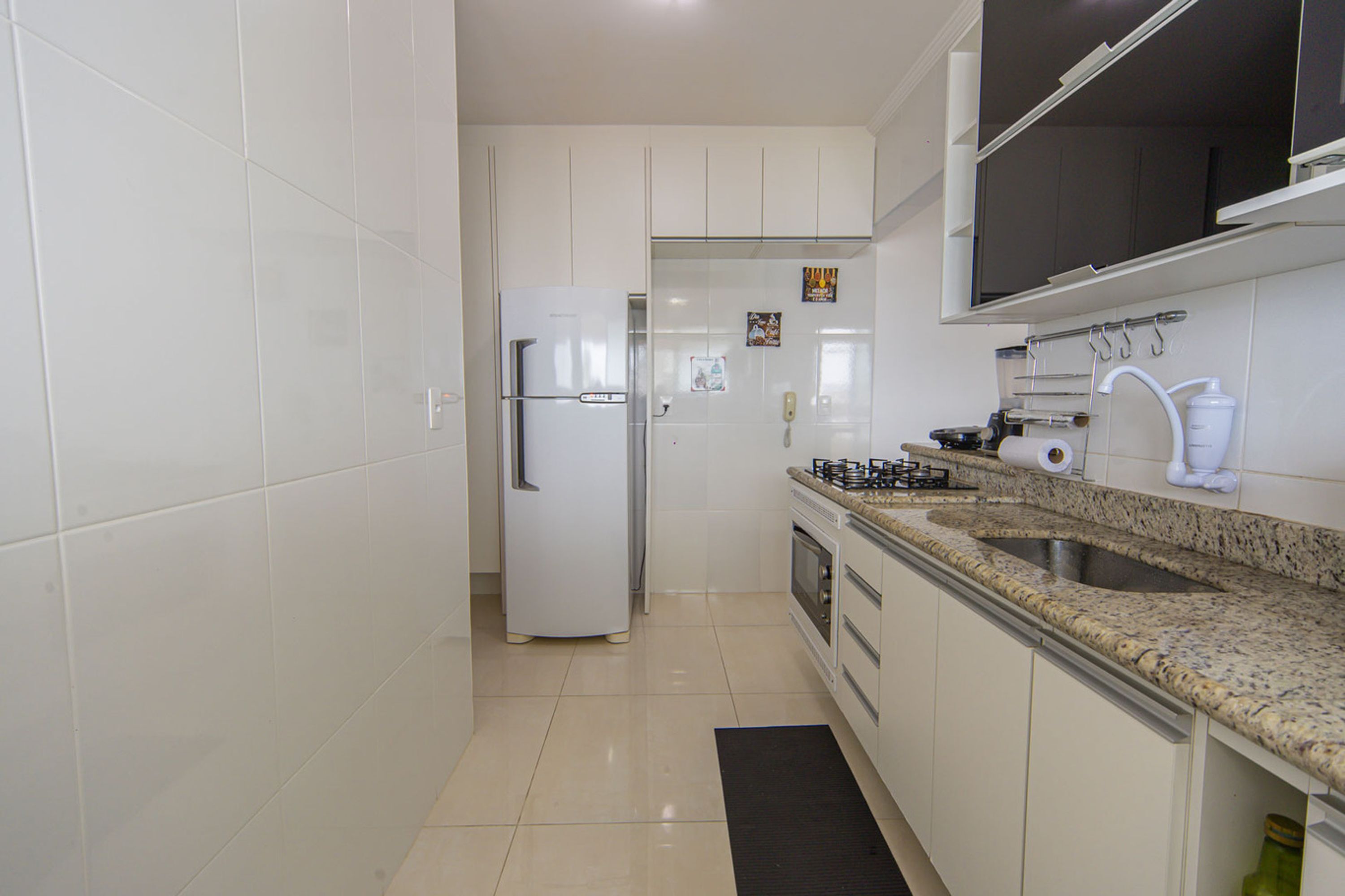 Una cocina con gabinetes blancos, un refrigerador blanco, una estufa y un lavaplatos.