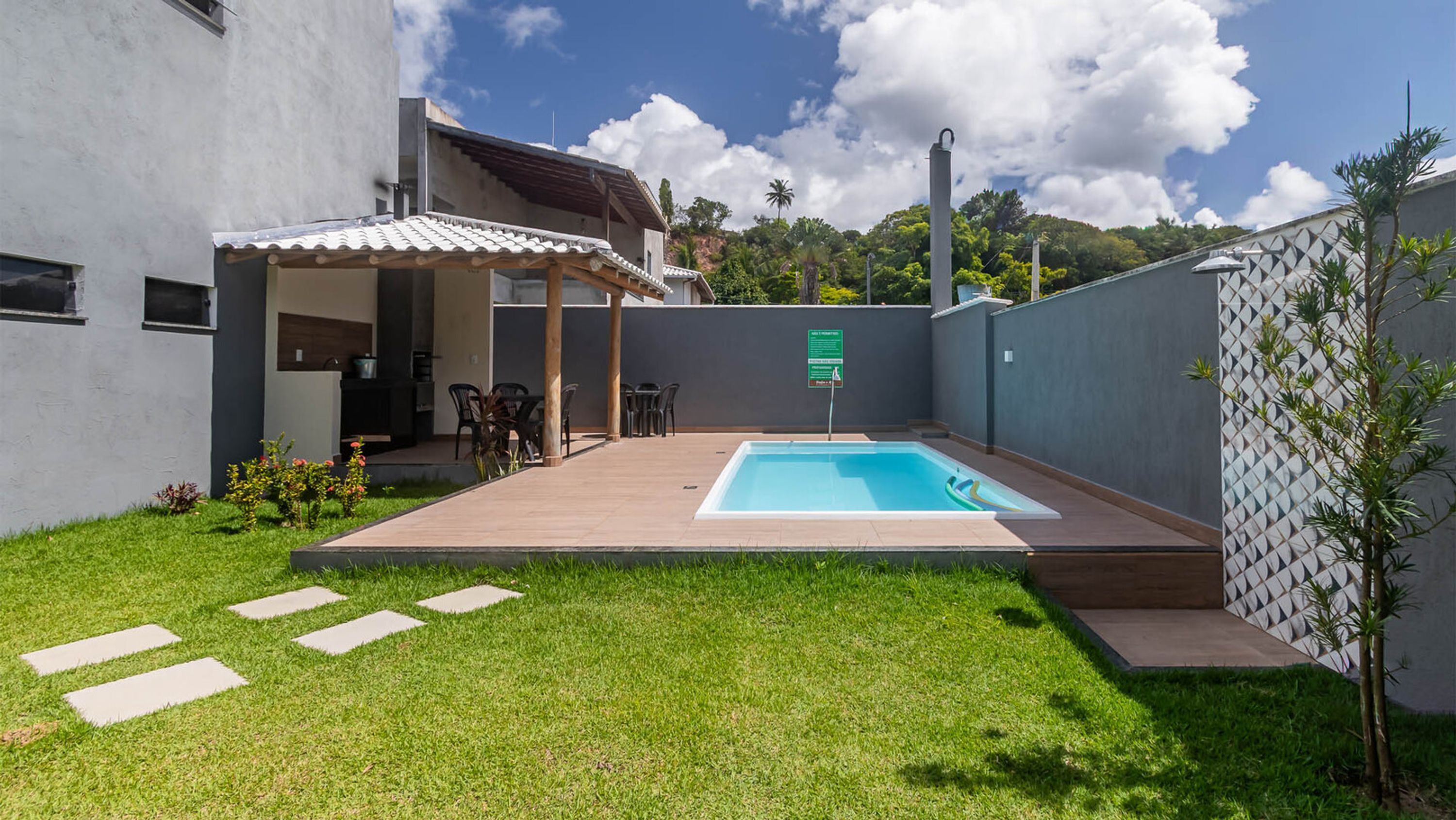 Un jardin avec une piscine, un patio couvert et un petit espace aménagé en jardin.