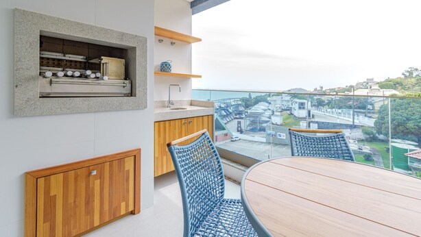 Eine moderne Küche mit Einbauofen, Holzschränken und Blick auf die Stadt durch große Fenster.