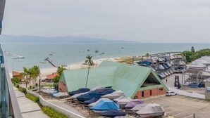 Blick auf einen Strand mit Booten, einen Parkplatz mit überdachten Fahrzeugen und ein Gebäude mit Gründach.