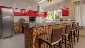 A modern kitchen with a central island, built-in oven, and bar stools.