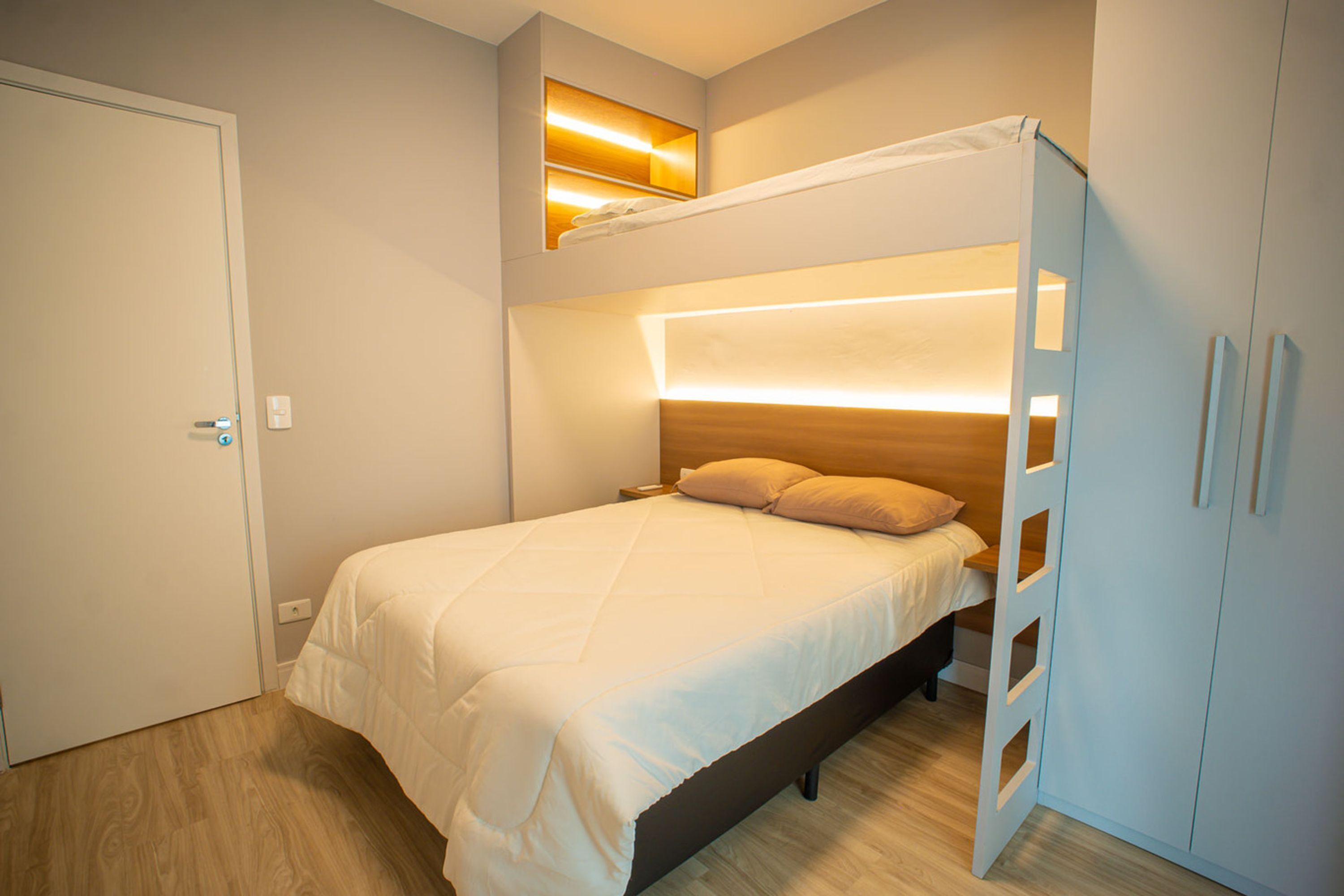 A bedroom with a bunk bed, a wardrobe, and a bedside table.
