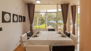 Comedor con una mesa dispuesta para cuatro personas, ventanas amplias con cortinas y un ventilador de techo.