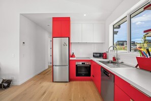 Una cocina moderna con armarios rojos, electrodomésticos de acero inoxidable y un ventanal con vistas al exterior.