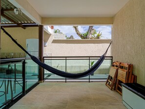 A balcony with a hammock, a glass railing, and a view of the outside. - Casa em Itaipua u c Hidro e Churrasqueira - Maric (Marica)