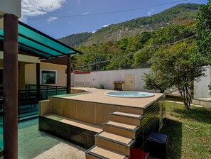 A hot tub area with steps leading up to it, surrounded by a garden and a building with a green roof. - Casa em Itaipua u c Hidro e Churrasqueira - Maric (Marica)