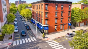 A multi-story brick building with a row of parked cars and a crosswalk. - 𖡡 Jazz Suite - King Bed Studio 15 Min to NYC (Hoboken)
