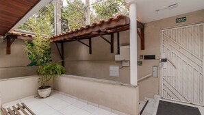 Un espace extérieur abrité comprenant un pot de fleurs, un banc, un escalier et un panneau indiquant une sortie de secours.