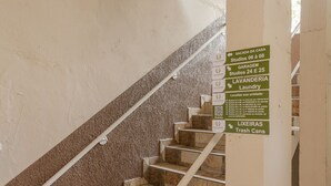 Un escalier avec des panneaux indicateurs indiquant les différents lieux, tels que « Garage », « Laverie » et « Poubelles ».