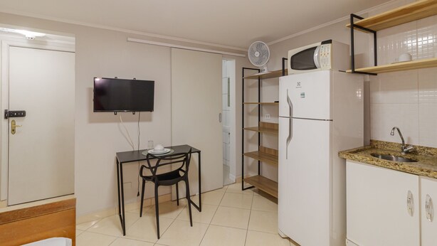 Une cuisine compacte équipée d’un four à micro-ondes, d’un réfrigérateur et d’une petite table à manger avec des chaises.