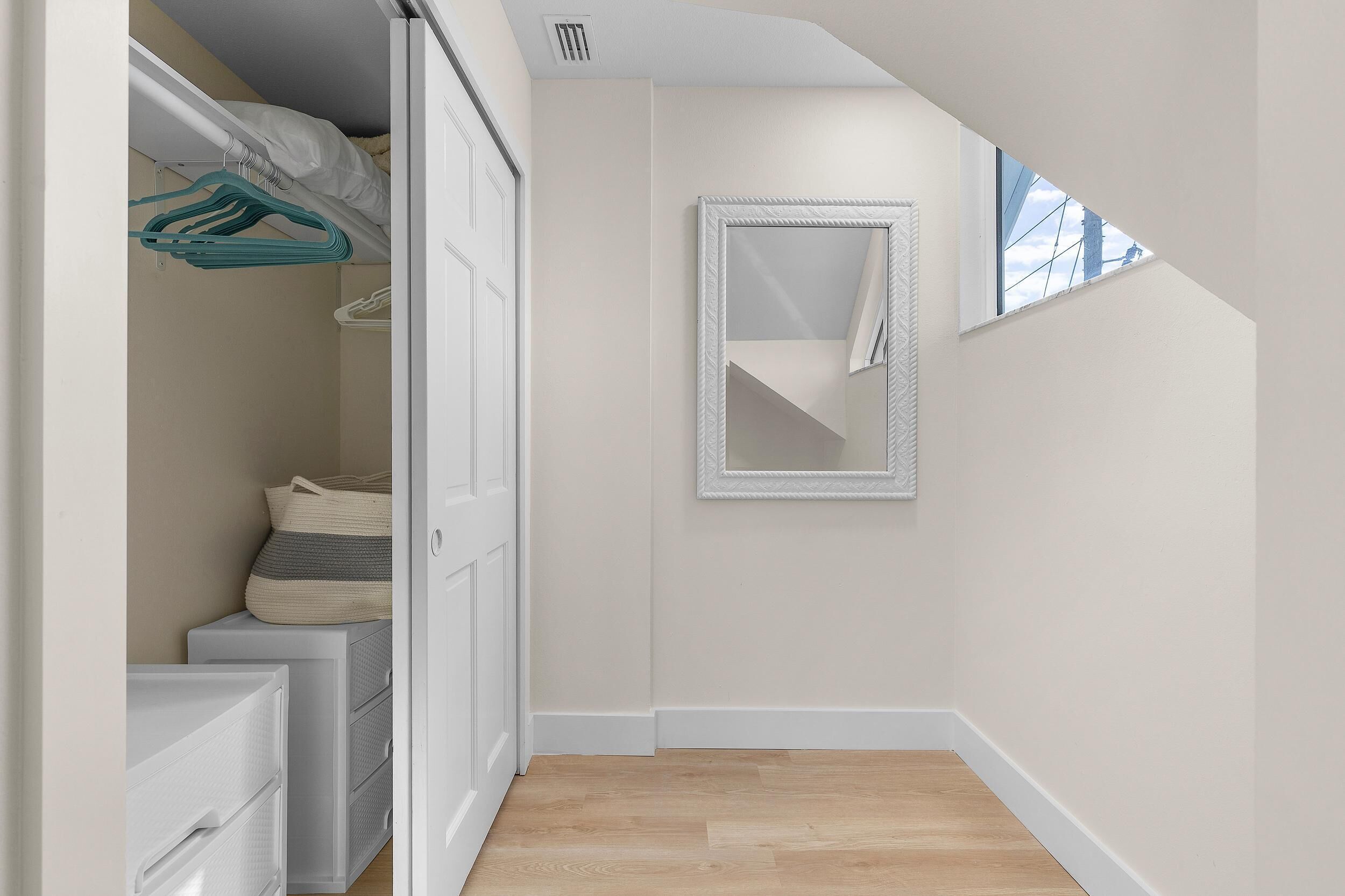 A bedroom with a closet, a mirror, and a window.