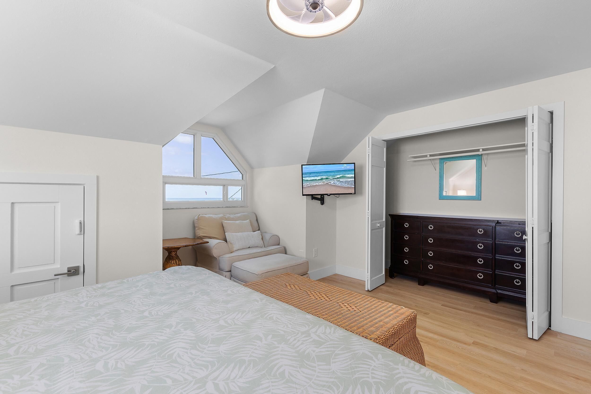 A bedroom with a bed, a dresser, a television, and a window.