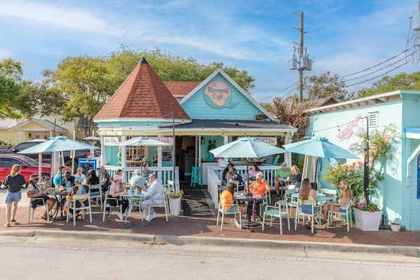 A seaside café with outdoor seating and a distinctive mermaid-themed sign. - Villa Bleu (New Smyrna Beach)