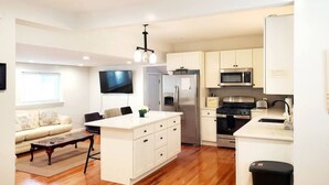 A modern kitchen with white cabinetry, stainless steel appliances, and a central island. - 3 Large Bedrooms | Modern Décor | Spacious (Everett)