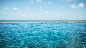 A clear view of a beach with calm waters and a distant shoreline. - Flat Beira-mar c Piscina e Academia em Mana ra (João Pessoa)