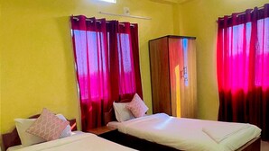 Una camera d'albergo con due letti, una ventola a soffitto e tende.