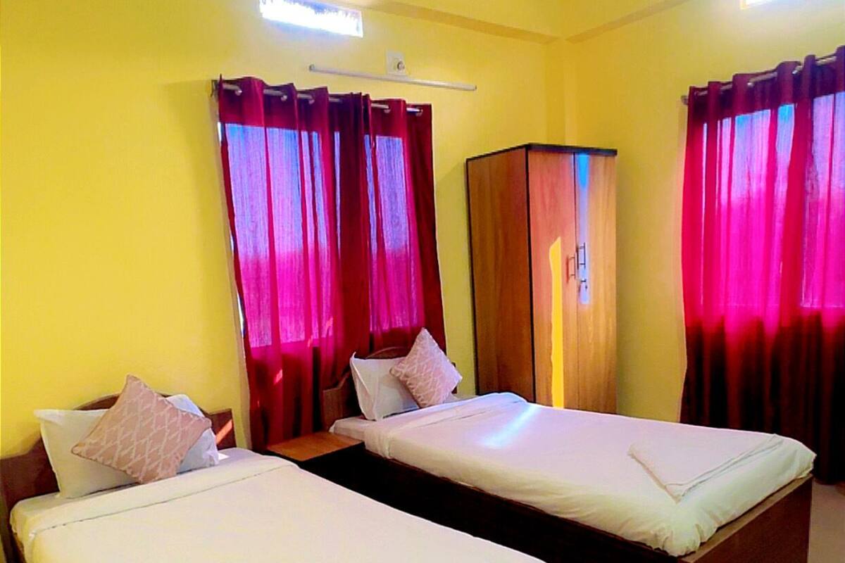 A hotel room with two beds, a ceiling fan, and curtains.