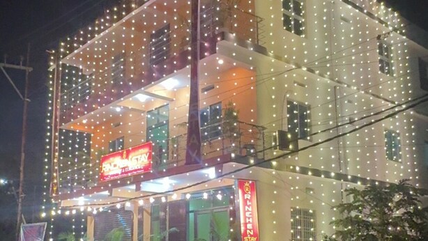 Un edificio con diversi piani, decorato con luci a stringa, e un cartello che recita 'RINCHEN STAY'.