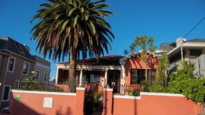 Una casa residenziale con facciata rossa, un cancello e una palma alta di fronte.