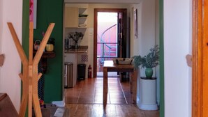 Un corridoio con pavimento in legno, parete verde e una porta che dà su un angolo cottura.