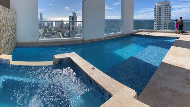 Ein Pool mit Blick auf die Stadt, Steinmauern und einer Glasuhr.