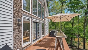 A deck with outdoor furniture, a table, and an umbrella. - Spacious 4-bedroom 7 Beds waterfront cottage in lovely Mooresville, private dock (Mooresville)