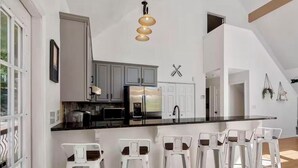 A modern kitchen with a large island, stainless steel appliances, and white bar stools. - Spacious 4-bedroom 7 Beds waterfront cottage in lovely Mooresville, private dock (Mooresville)