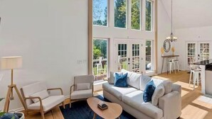 A spacious living room with a high ceiling, large windows, and a view of the outdoors. - Spacious 4-bedroom 7 Beds waterfront cottage in lovely Mooresville, private dock (Mooresville)