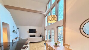 A spacious living area with a dining table, chairs, a fireplace, and large windows. - Spacious 4-bedroom 7 Beds waterfront cottage in lovely Mooresville, private dock (Mooresville)