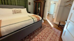 A bedroom with a four-poster bed, a patterned rug, and a wooden bench. - Boutique Historic Stay • Best Downtown Location (Savannah)
